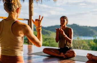 Two women practicing yoga on an ocean view deck at Eden on the Chocolata retreat, San Juan del Sur, Nicaragua