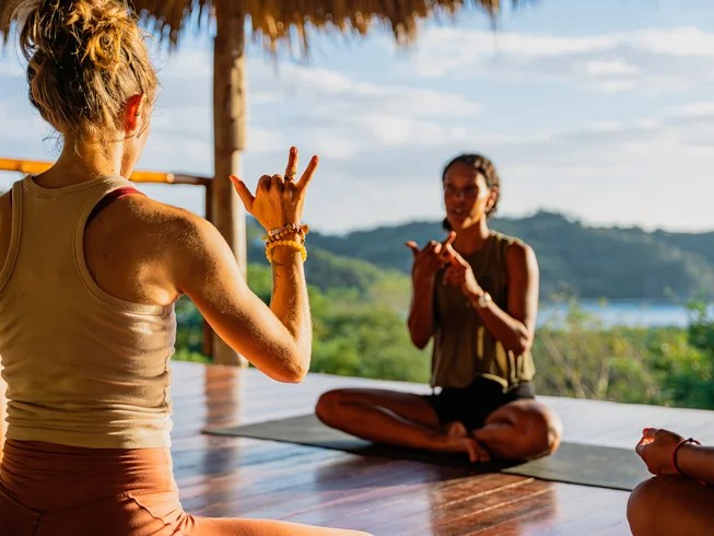 Two women practicing yoga on an ocean view deck at Eden on the Chocolata retreat, San Juan del Sur, Nicaragua